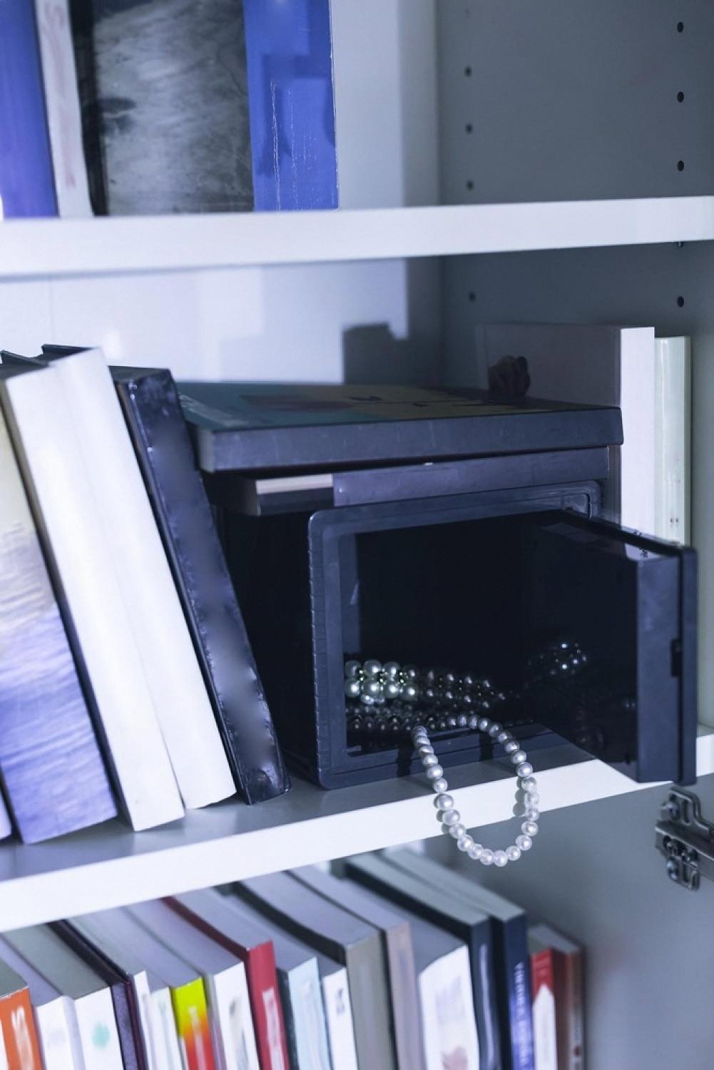 Small burglar-proof safe hidden on a bookshelf with jewellery inside